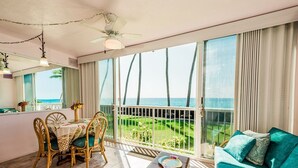 Una habitación con balcón que da al mar, amueblada con una mesa, sillas y un sofá.
