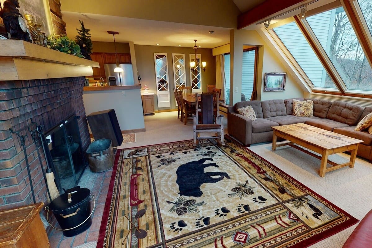 Una sala de estar acogedora con chimenea, un tapete grande y un sofá.