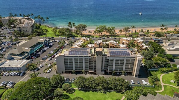 A hotel with a parking lot, a beach view, and solar panels on the roof.