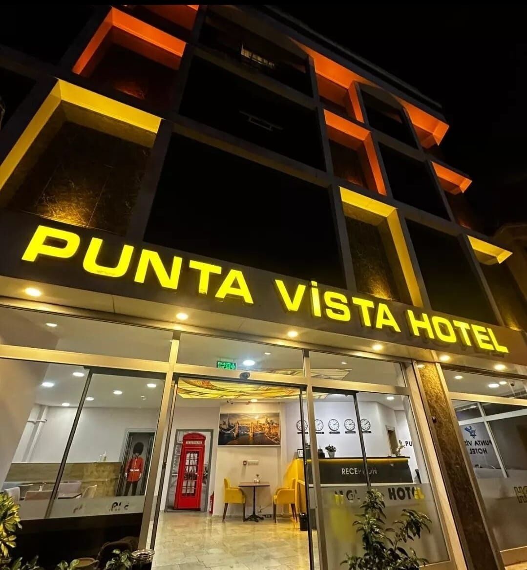 Exterior del Hotel Punta Vista con una mesa de recepción, un teléfono rojo y una vista despejada de la entrada.