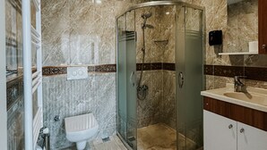 A modern bathroom with a glass-enclosed shower, a toilet, and a sink with a mirror above it. - Punta Vista Otel (Izmir)