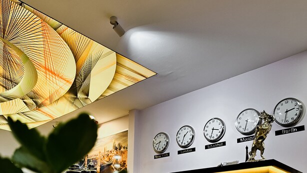 A reception desk with clocks indicating different cities, a reception sign, and a decorative ceiling light. - Punta Vista Otel (Izmir)