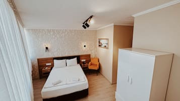 Ett hotellrum med en säng, sängbord, en stol, en garderob och en vägg med ett geometriskt mönster och en tavla.