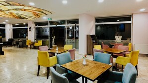 A spacious indoor area with multiple tables and chairs, a ceiling with a decorative pattern, and a visible exit sign. - Punta Vista Otel (Izmir)