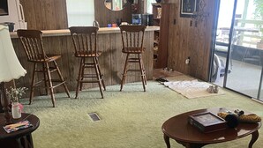 Een gezellige woonkamer met een bar, een eettafel en een bank.
