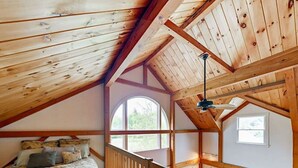 Ein Schlafzimmer mit Holzboden, einem Bett mit Kissen, einem Fenster und einer Treppe.