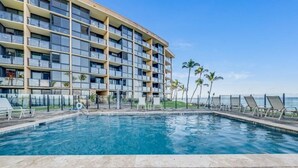 A hotel with a swimming pool, lounge chairs, and a view of the ocean. - Kihei Surfside, #111 1 Bedroom Condo by RedAwning (Kihei)