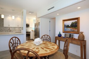 A dining area with a round table, chairs, and a painting on the wall. - Wailea Elua, #1309 1 Bedroom Condo by RedAwning (Kihei)