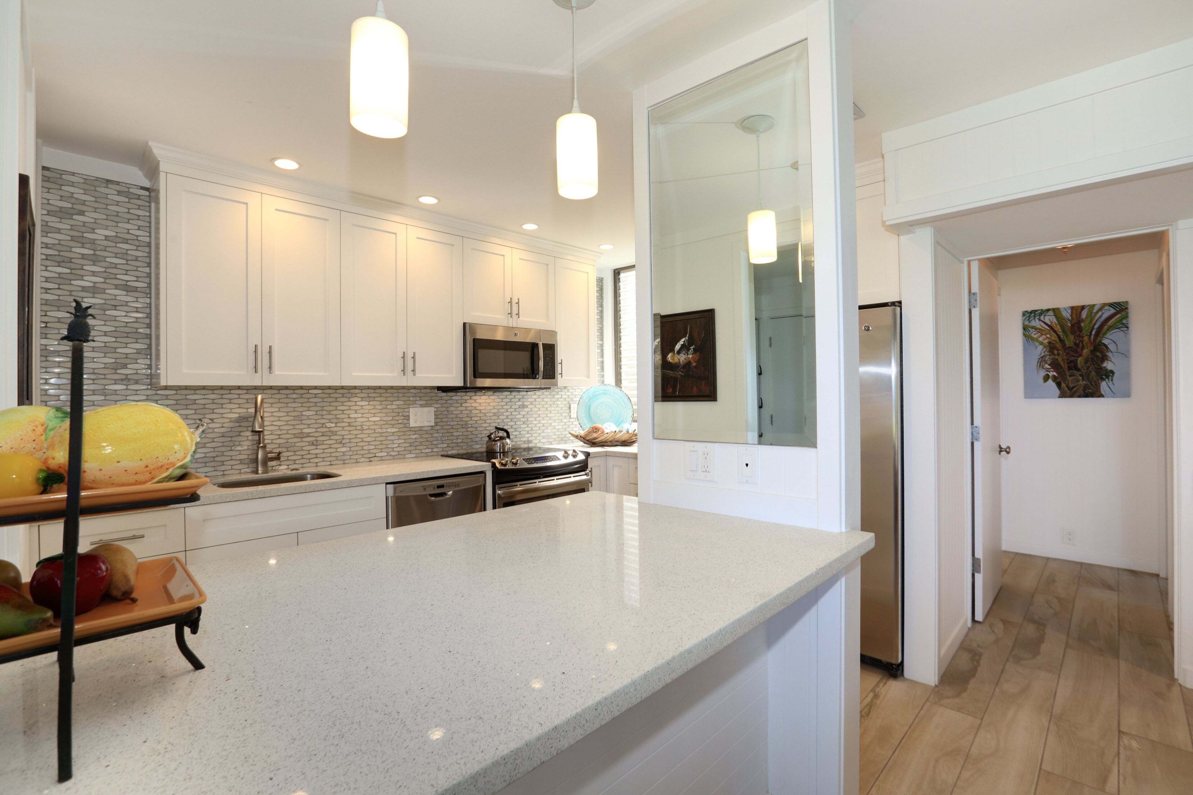 A modern kitchen with white cabinetry, stainless steel appliances, and a large island.