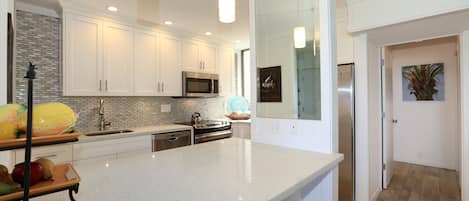 A modern kitchen with white cabinetry, stainless steel appliances, and a large island.