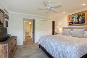 A bedroom with a bed, a ceiling fan, a TV, and artwork on the wall. - Wailea Elua, #1309 1 Bedroom Condo by RedAwning (Kihei)