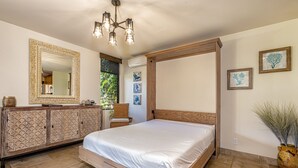 A bedroom with a four-poster bed, a dresser, a mirror, and wall art. - Wailea Ekahi, #33b 1 Bedroom Condo by RedAwning (Kihei)