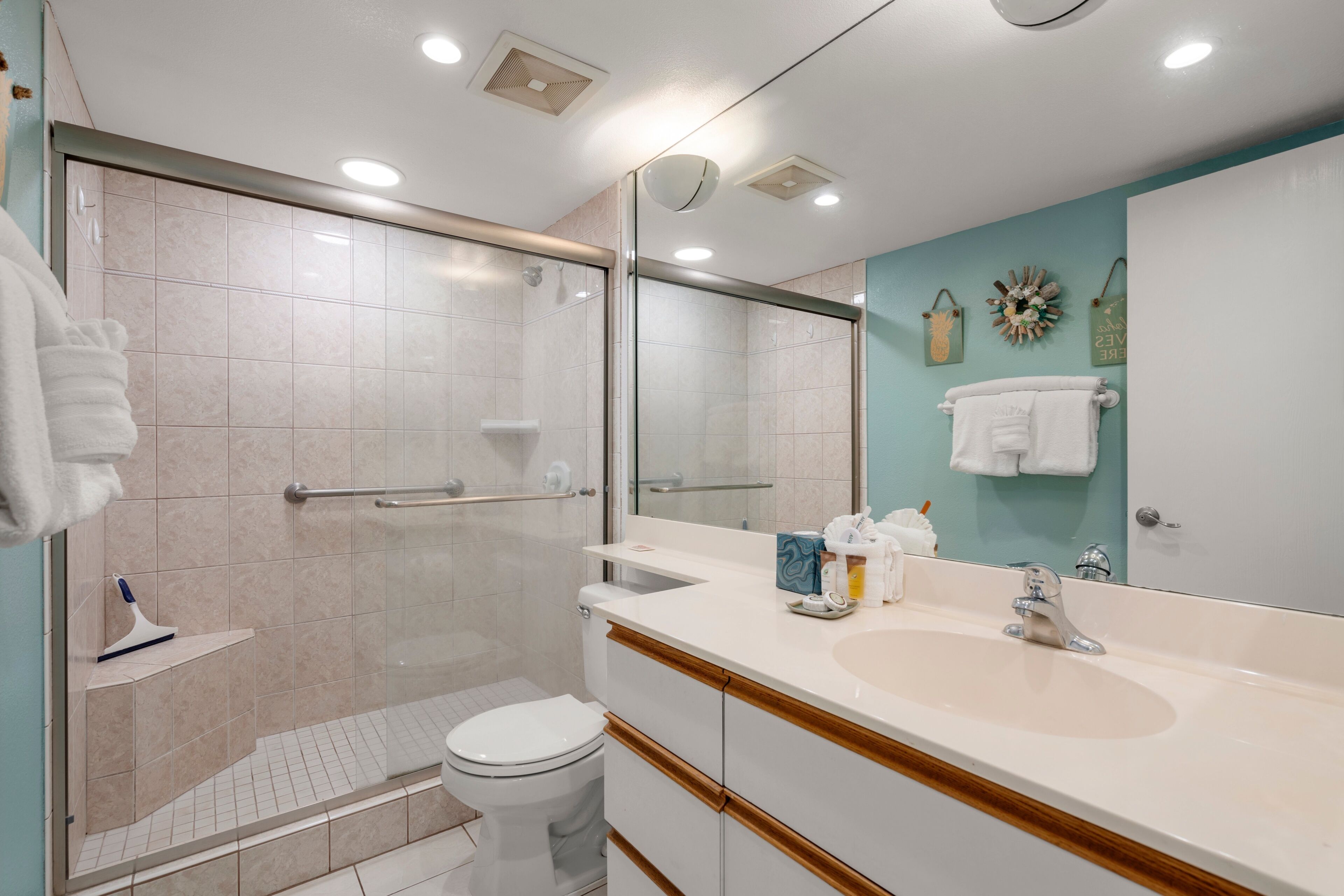A modern bathroom with a glass-enclosed shower, a white toilet, a vanity with a mirror, and a sink.