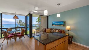 A spacious room with a large sliding glass door leading to a balcony with a view of the ocean. - Kihei Surfside, #508 1 Bedroom Condo by RedAwning (Kihei)