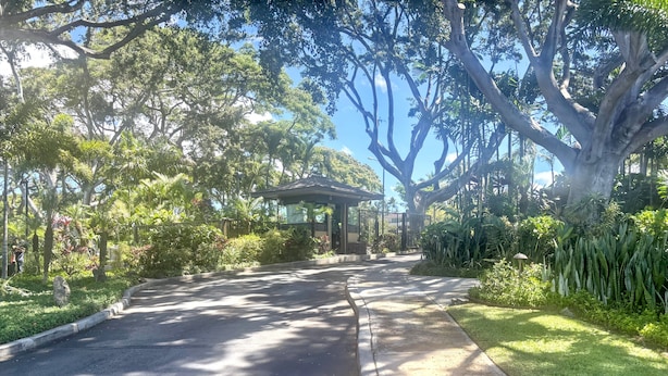 A paved driveway leading to a building with a covered entrance, surrounded by lush greenery and trees. - Wailea Elua, #0908 2 Bedroom Condo by RedAwning (Kihei)