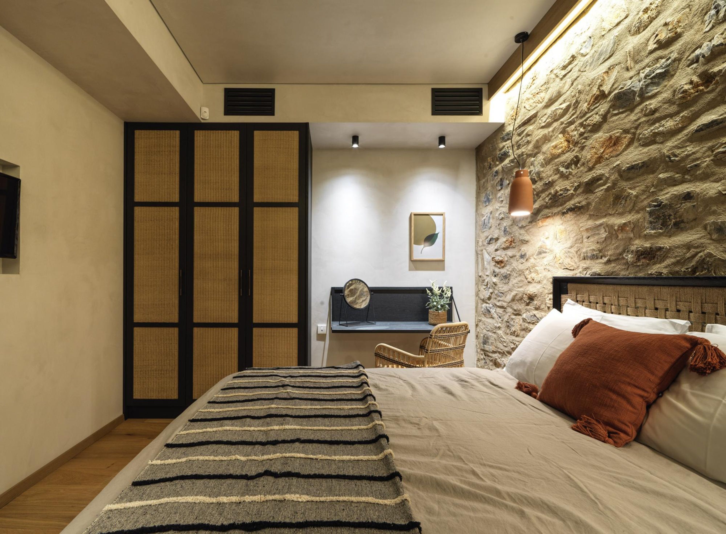 Une chambre à coucher avec un lit, un bureau et un mur en pierre.