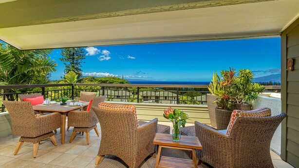A covered outdoor seating area with wicker furniture and a view of the ocean. - Kapalua Golf Villas by Coldwell Banker Island Vacations (Lahaina)