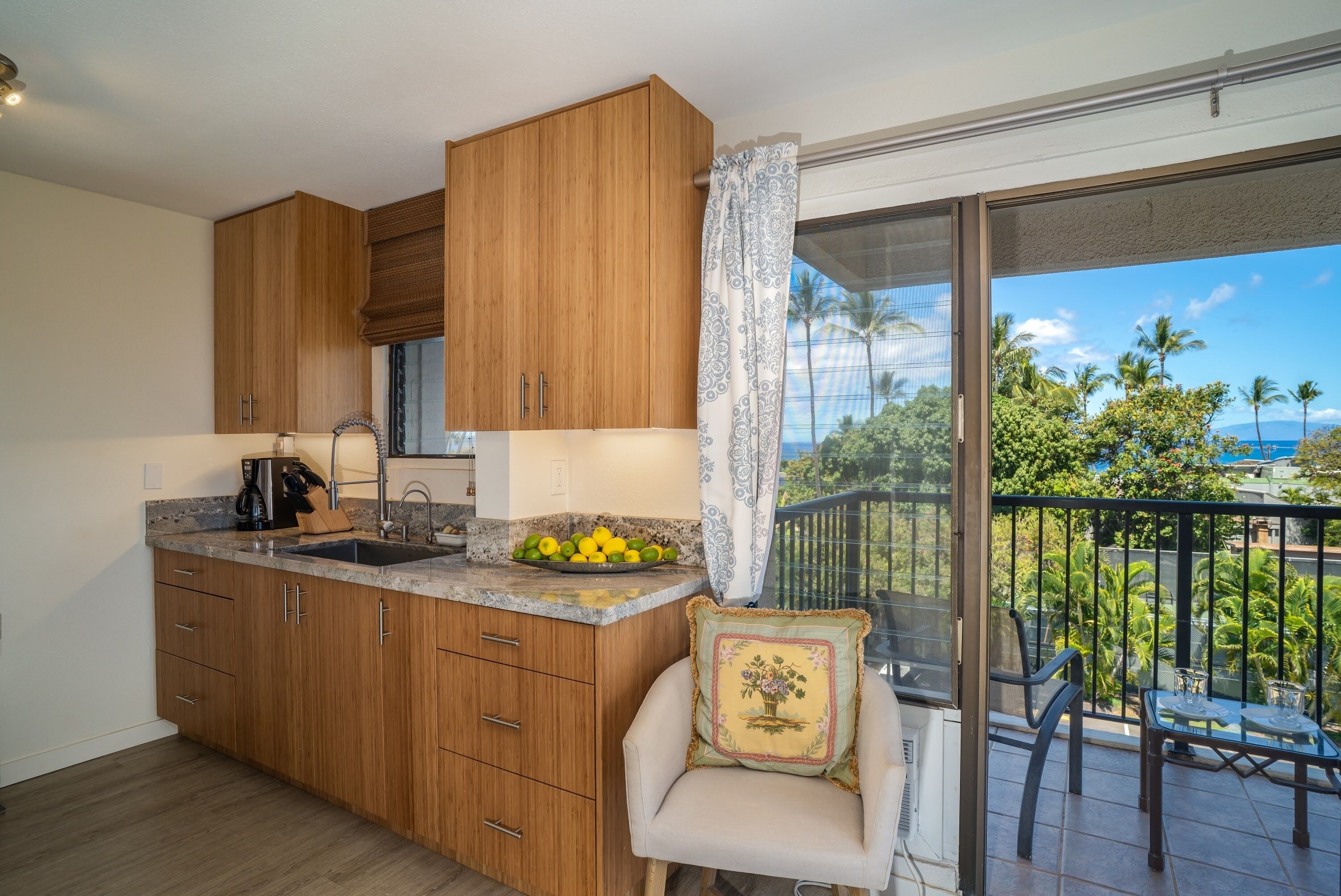 Una cocina con armarios de madera, un lavamanos y una zona de comedor con una silla y una mesa.