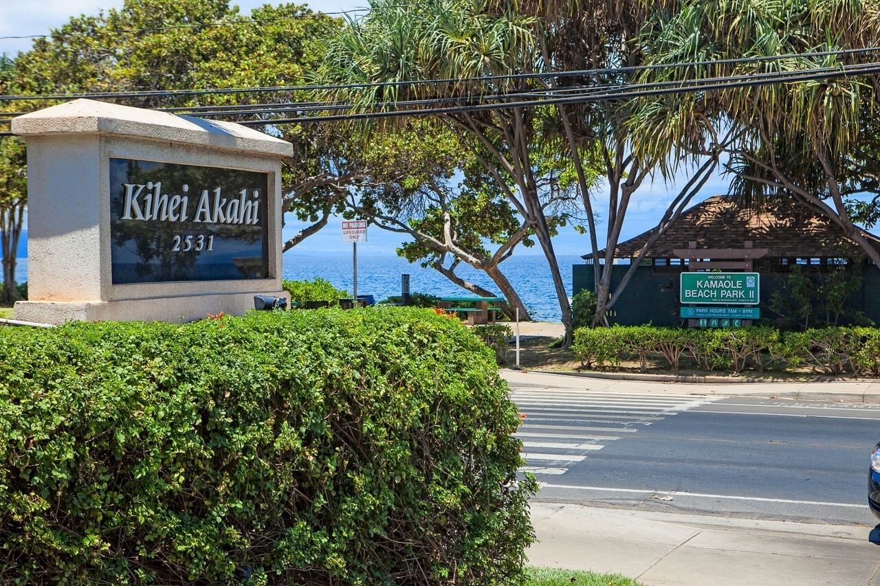 A sign for Kihei Akahi with a beach park and lifeguard station nearby.
