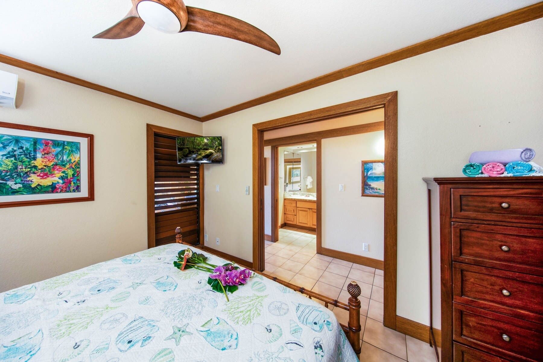 A bedroom with a bed, wooden dresser, and a ceiling fan.