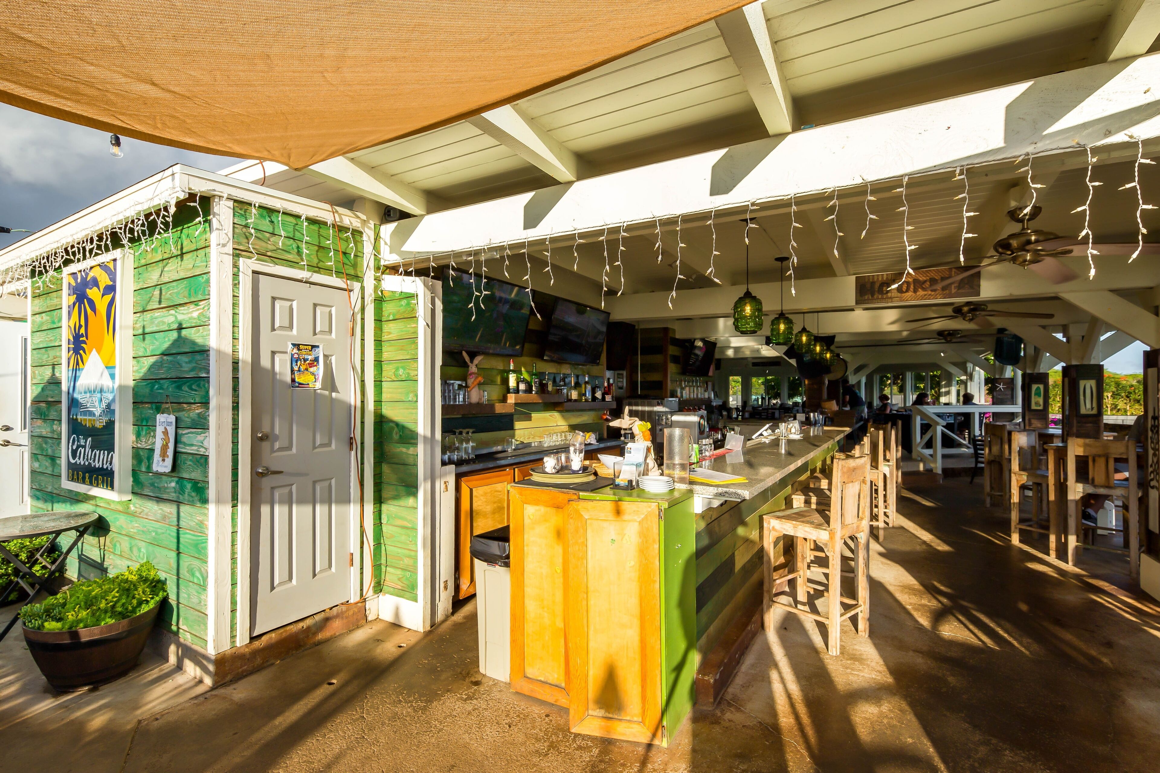 A restaurant with a green exterior, a bar area with wooden stools, and a counter with a sink.