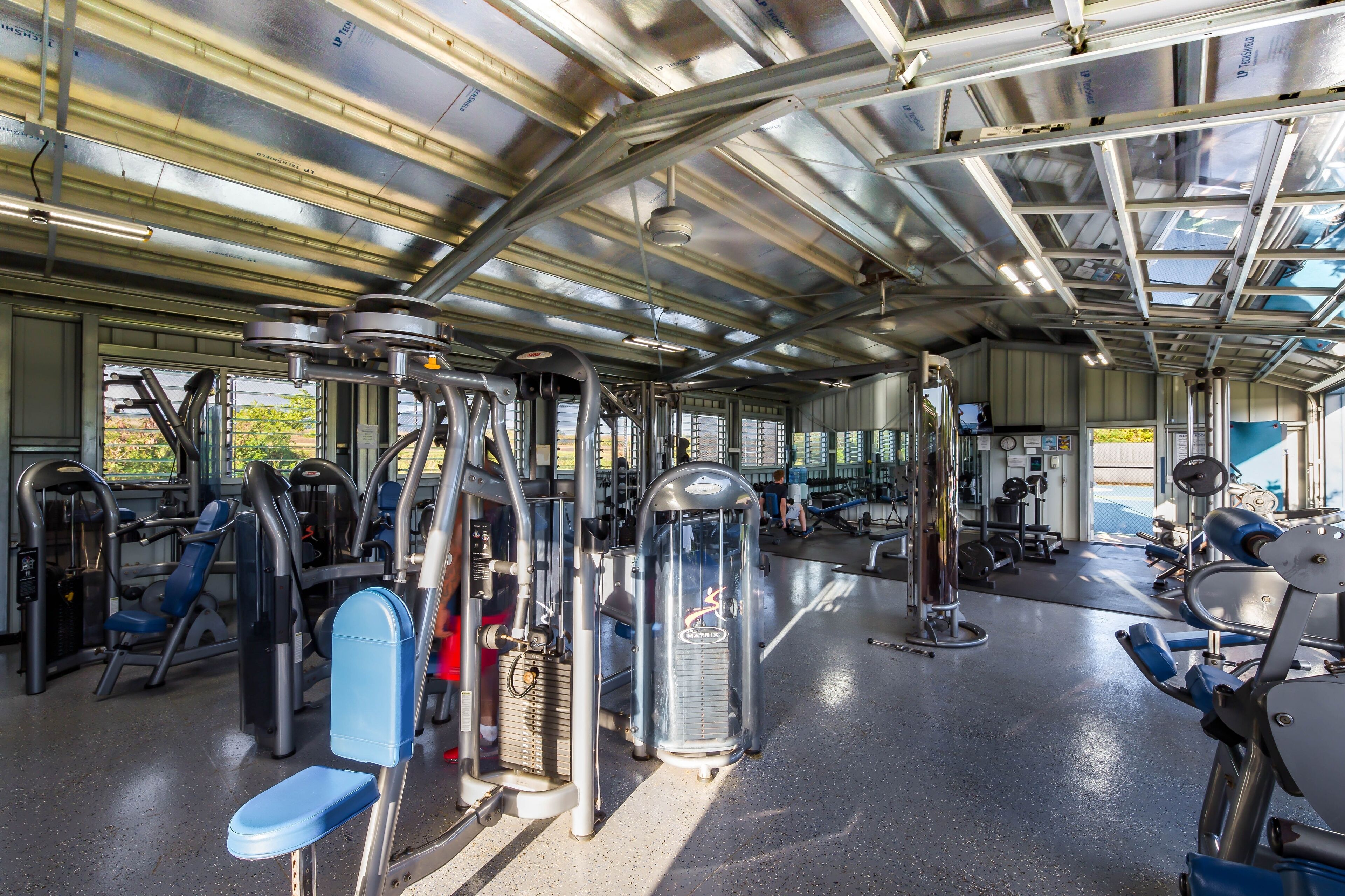 A gym with various exercise machines, a ceiling with skylights, and a view of the outdoors.