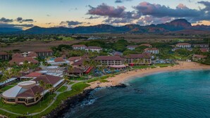 A coastal resort with beachfront villas, a swimming pool, and a view of the ocean and mountains. - Kauai Kiahuna Plantation by Coldwell Banker Island Vacations (Koloa)