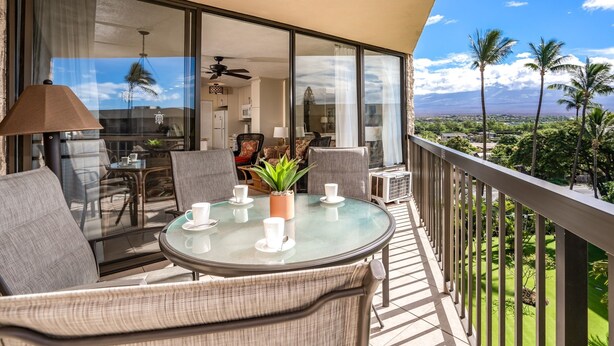 A balcony with a glass table, chairs, and a potted plant. - Maui Sunset A504 1 Bedroom Condo (Kihei)