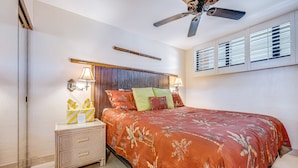A hotel room with a bed, a nightstand, a ceiling fan, and a window with blinds. - Kihei Surfside, #609 1 Bedroom Condo by RedAwning (Kihei)