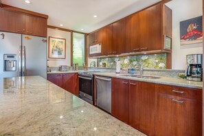 Una cocina moderna con gabinetes de madera, electrodomésticos de acero inoxidable y encimera de granito.