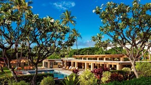 Un resort con piscina, palme e un edificio moderno con lettini.