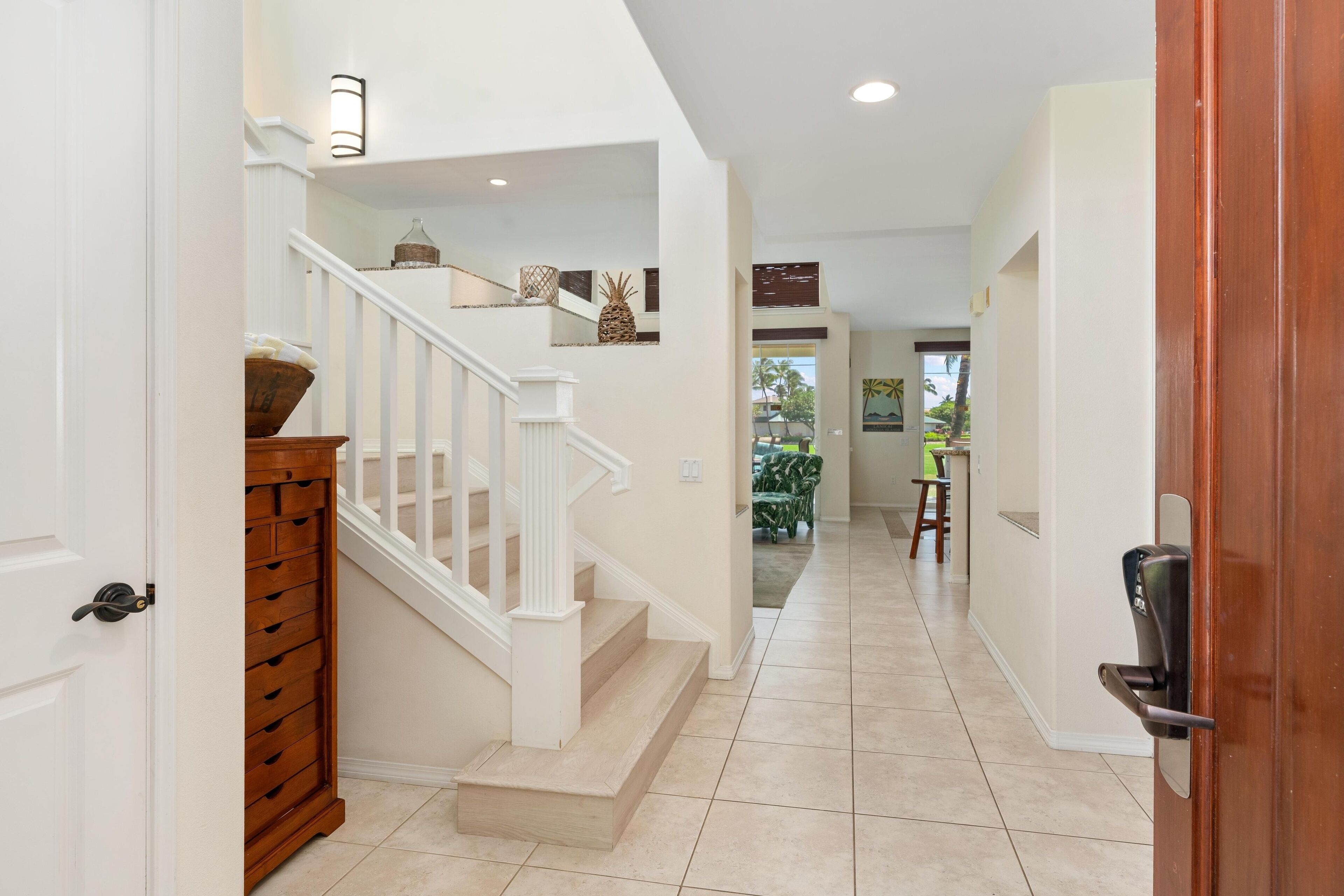 A clean, well-lit hallway with a wooden staircase and a door on the right.