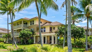 A two-story house with a balcony, surrounded by palm trees and a well-maintained lawn. - Big Island Fairway Villas by Coldwell Banker Island Vacations (Waikoloa)