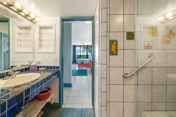 Un baño con lavamanos, espejo y zona de ducha.