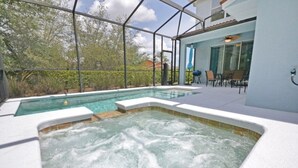Un área de piscina con un jacuzzi y un patio cubierto con sillas y una mesa.