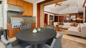 A modern kitchen with a built-in stove, wooden cabinets, and a dining area with a round table and wicker chairs.