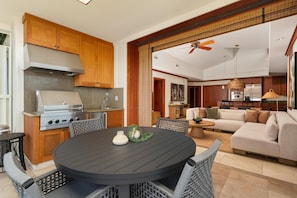 Una cocina moderna con estufa integrada, armarios de madera y un comedor con mesa redonda y sillas de mimbre.