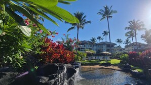 A tropical resort with a waterfall, palm trees, and a pool area.