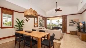 A dining area with a wooden table and chairs, a ceiling fan, and a view of the outdoors.