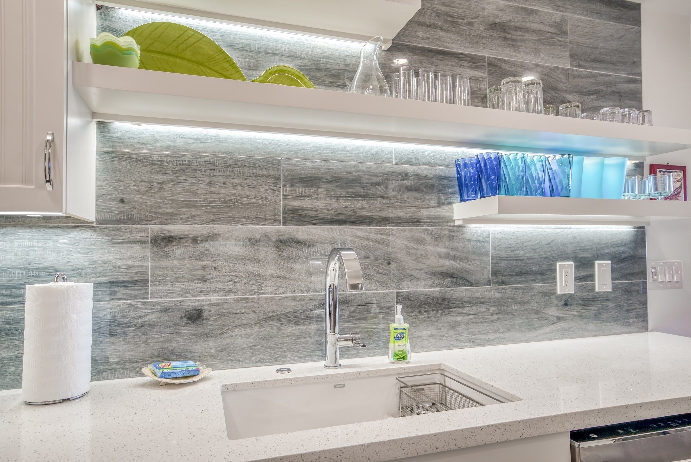 A modern kitchen with a stainless steel sink, a dish rack, and a soap dispenser.