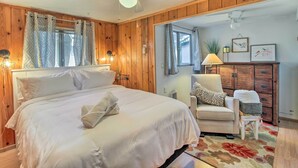 Un dormitorio con cama, una silla, cómoda y ventilador de techo.