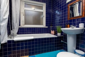 A bathroom with a bathtub, sink, and toilet. - Serene and Spacious 1 Bedroom Garden Flat in Clapton (London)