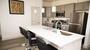 Una cucina moderna con isola centrale, elettrodomestici in acciaio inossidabile e sgabelli da bar.