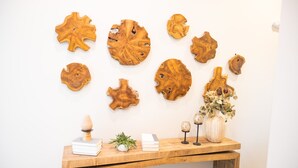 Un tavolo di legno con libri, una pianta e oggetti decorativi, su uno sfondo di parete bianca con decorazioni in legno.