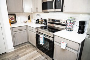 Una cocina moderna con electrodomésticos de acero inoxidable, armarios blancos y salpicadero de azulejos.