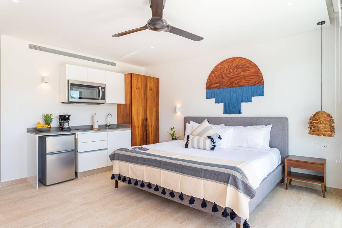 A modern bedroom with a bed, bedside table, and a built-in microwave.