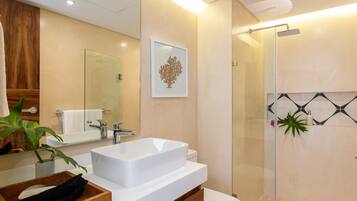 Une salle de bain moderne avec un grand lavabo blanc, une douche en verre et un meuble-lavabo en bois.