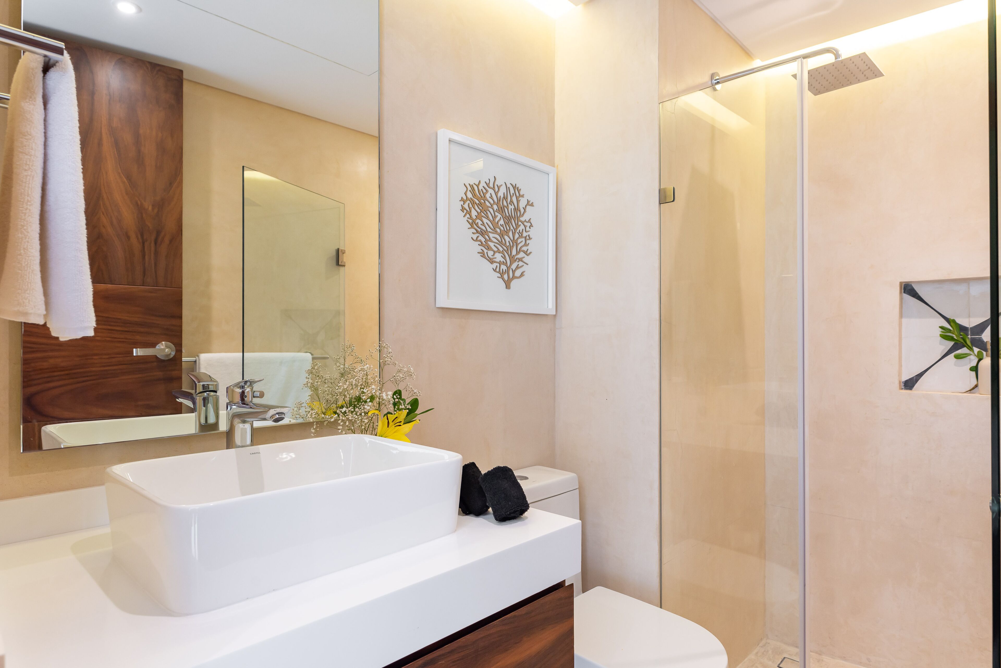 Un bany modern amb una banyera blanca gran, una cabina de dutxa de vidre i un moble de tocador de fusta.