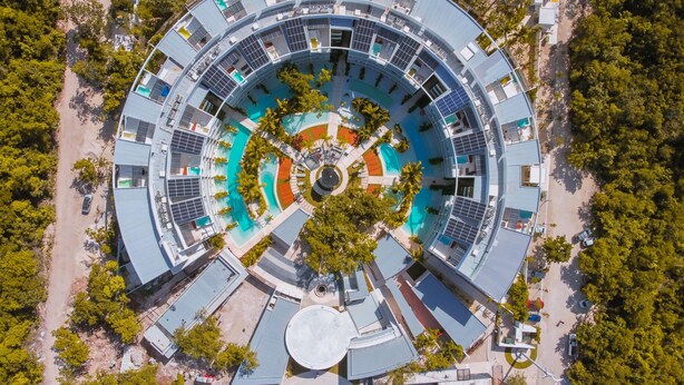 Un edificio circular con un patio central, varios balcones y una piscina.