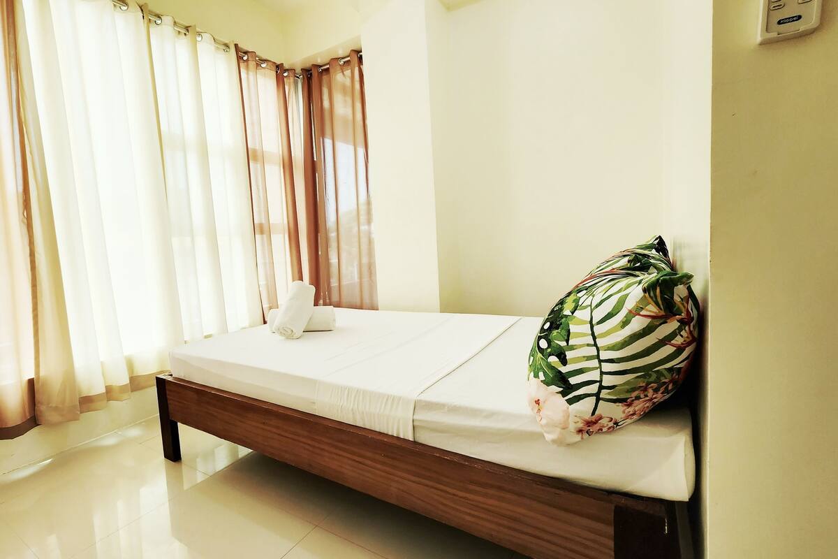 A bedroom with a wooden bed, white bedding, and a floral pillow.